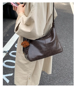 Détail d'un grand sac bandoulière marron vintage avec un joli charme d'ours en peluche