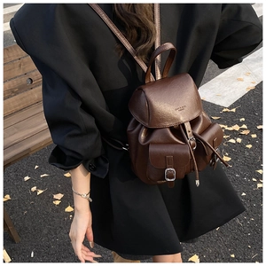 Close-up of a vintage dark brown faux leather backpack with drawstring and buckle detail