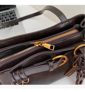 Gros plan de la fermeture éclair dorée et du détail de la boucle sur le sac en cuir marron
