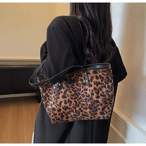 Detail of leopard print tote bag with black leather straps and gold rivet accents