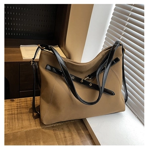 Détail du sac en suédine marron avec lanières noires et œillets métalliques