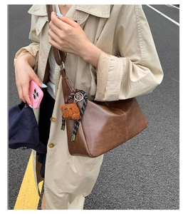 Détail d'un sac hobo en cuir huilé marron avec charm ours et cordon tressé décoratif