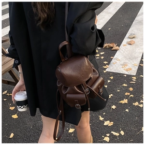 Street view of a vintage dark brown faux leather backpack with metallic buckle details