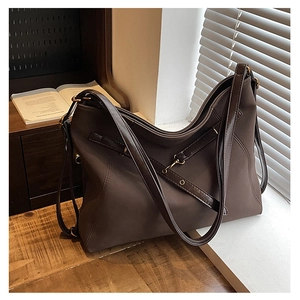 Détail du sac bandoulière en daim café avec œillets métalliques et sangle latérale