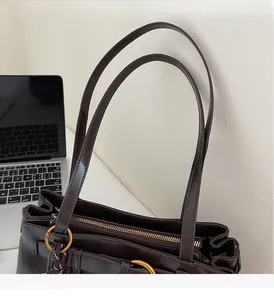 Détail des anses en cuir marron et des ferrures en métal doré sur le sac cabas