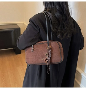 Detail showing the dark brown suede hobo bag with gold lettering and tassel knots