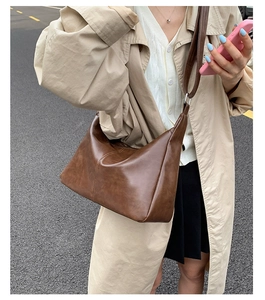 Détail d'un sac cabas vintage en cuir souple marron foncé avec coutures verticales