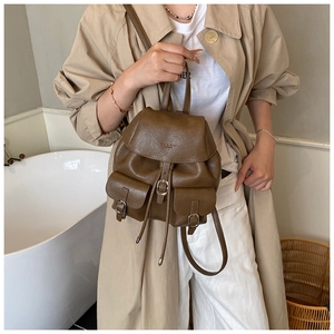 Brown retro leather backpack styled by a model in a minimalist room setting