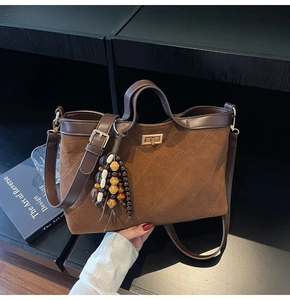 Detailansicht der braunen Wildledertasche mit Goldverschluss und Perlenanhänger