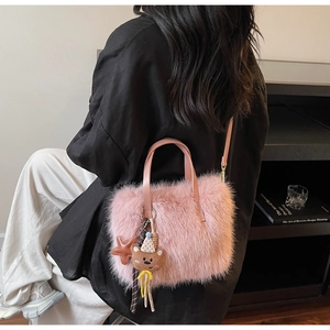 Sac à main en fausse fourrure rose avec pendentif ours présenté en mode porté épaule