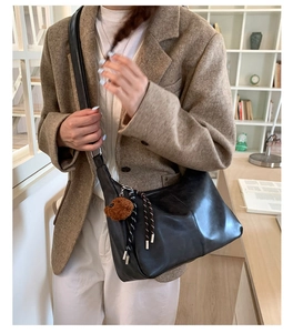 Détail d'un grand sac cabas en cuir noir avec un pendentif d'ours en peluche marron mignon