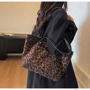 Detailed view of leopard print tote bag with black leather straps and gold metal hardware