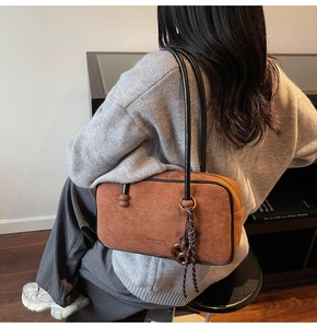 Close-up of brown suede shoulder bag with black trim and vintage brand logo detail