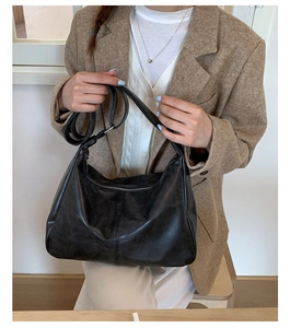 Détail d'un sac hobo en cuir noir mat avec fermeture éclair métallique et bandoulière réglable