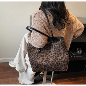 Detail of leopard print tote bag with black leather straps on a knit sweater shoulder