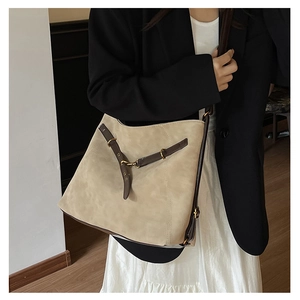 Vue détaillée du grand sac à bandoulière en daim beige avec lanières marron et anneaux métal