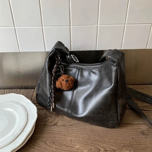 Détail du sac hobo en similicuir noir avec pendentif ours en peluche et zip