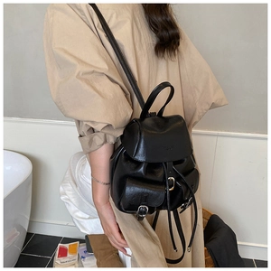 Detail view of stylish black matte synthetic leather backpack with flap and drawstring closure