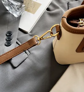 Dettaglio della ferramenta dorata e cuciture in pelle su borsa a secchiello bicolore