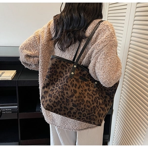 Detail of leopard print tote bag with black straps and gold rivets shown on model