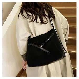 Détail du grand sac porté épaule noir en daim avec lanières décoratives et boucles en métal