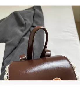 Detail of brown PU leather bag with comfortable handle and white crochet side decor