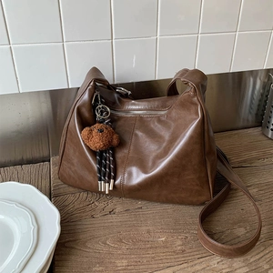 Détail du sac à bandoulière en similicuir marron foncé avec breloque ours en peluche