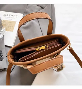 Dettaglio della borsa a secchiello in pelle marrone con zip in ottone e ciondolo gufo