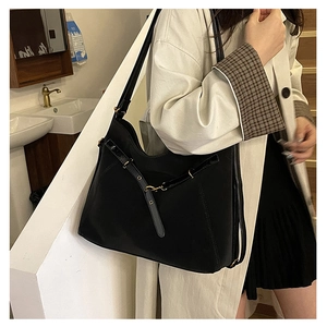 Détail d'un grand sac cabas en daim noir avec sangles décoratives et boucles en métal doré