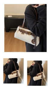 Détail du sac à bandoulière en toile avec garniture en cuir brun et breloque bretzel