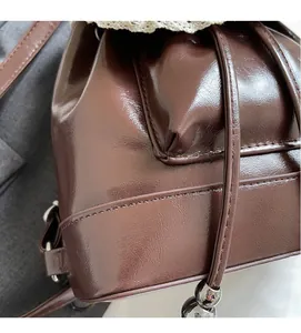 Close-up of retro dark brown glossy leather backpack featuring drawstring and silver beads