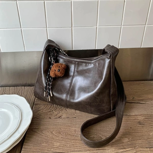 Détail du sac cabas marron foncé avec fermeture éclair argentée et breloque ours