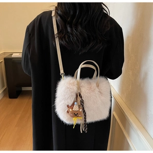 Sac à main chic en fausse fourrure crème avec pendentif ours sur un blazer noir élégant