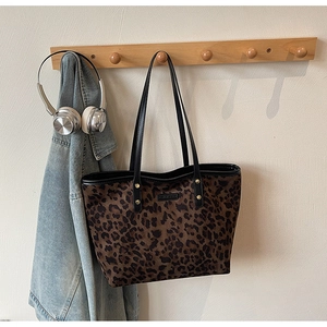 Detailed close-up of leopard print tote bag hanging with denim jacket and headphones