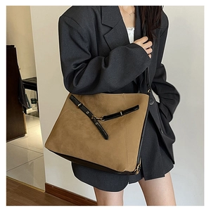 Détail d'un grand sac à bandoulière en daim marron avec sangle en cuir noir et boucle dorée