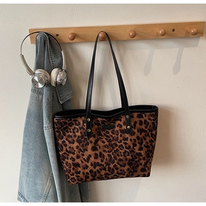 Detail of leopard print tote bag with black leather handles hanging in a cozy setting