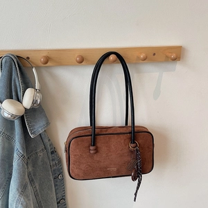 Detailed view of the brown suede shoulder bag with black leather handle and logo