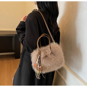 Détail d'un sac à bandoulière en peluche avec lanières en cuir et pompons tissés