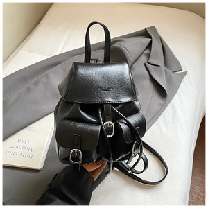 Close-up of black PU leather backpack with silver buckles on a grey blazer background