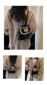 Detail view of black glossy PU backpack with white lace trim and cute bear patch