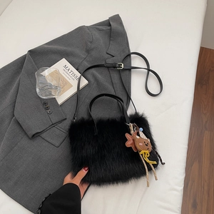 Vue de dessus d'un sac cabas en peluche noire avec breloques et bandoulière en cuir