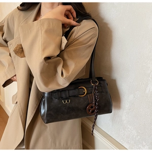 Détail d'un sac à bandoulière en cuir marron foncé avec boucle et breloque décorative