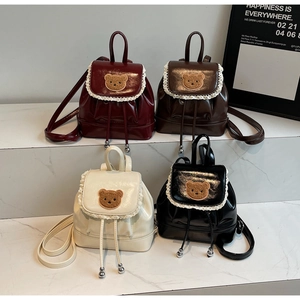 Detail of four colorful mini backpacks with cute bear patches and lace trim decorations