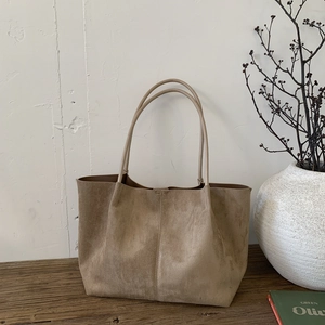 Detail of premium khaki suede tote bag on a vintage wood desk with soft lighting