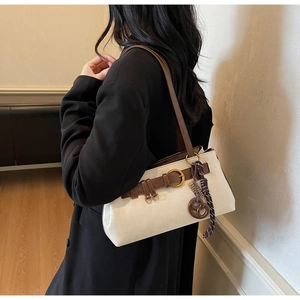 Détail d'un sac sous le bras blanc crème minimaliste avec bandoulière marron et boucle