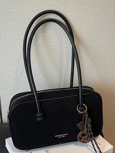 Minimalist black suede shoulder bag with long handles and brand logo for commuting