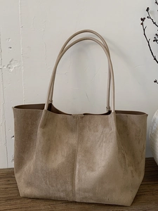 Minimalist camel suede tote bag with large capacity on rustic wooden surface