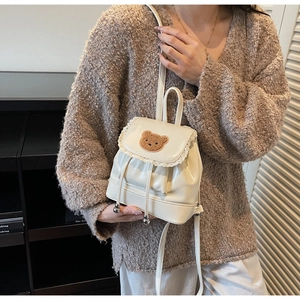 Detailed view of the cream mini backpack featuring lace trim and a cute plush bear patch