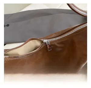 Detail shot of the silver metal zipper and brand logo on this large brown tote bag