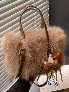 Sac cabas en peluche marron avec lanières en cuir et breloque ours dans un décor chaleureux